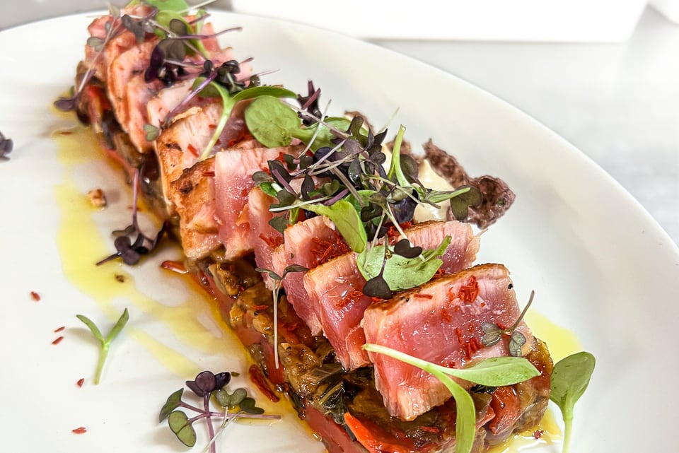 Rotes geschnittenes Thunfischsteak mediterraner Art auf Auberginen, rotem Paprika Caponata mit Pinienkernen, taggiasche Oliven und geröstetem Tomatenöl