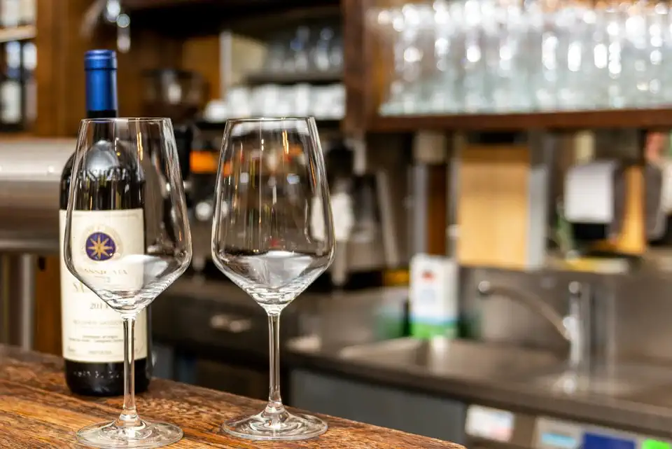 Weinflasche und zwei Weingläser stehen auf der Bar.
